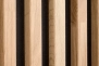 Detail der natürlichen Eichenholzlamellen auf schwarzem MDF-Hintergrund für Wandverkleidung