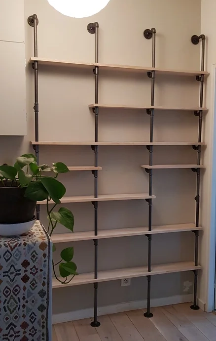 Make a custom shelf with wooden planks and plumbing pipes