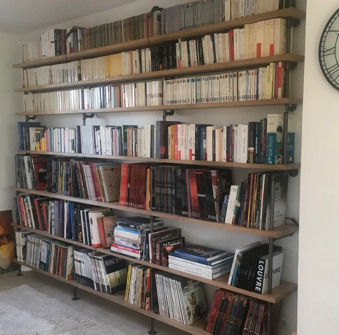 DIY bookcase construction with oak planks and combination of cast iron pipes