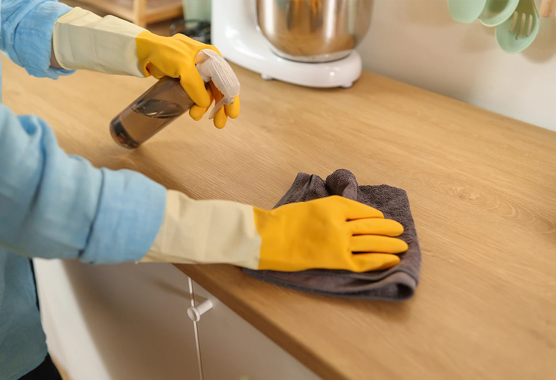 personne en train de nettoyer un plan de travail en bois